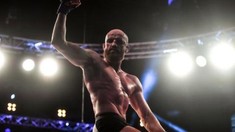 Peter Queally celebrates a win on the top of the cage