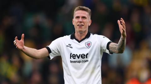 Emil Riis holding his arms in the air while standing on the pitch