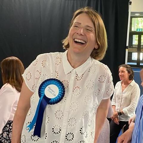 A woman wearing a rosette, laughing