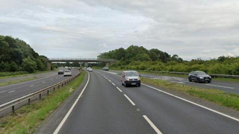 Cars driving along a stretch of dual carriageway, with another car driving on a slip road.