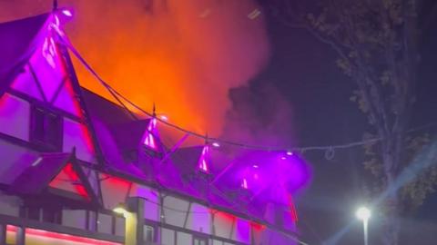 Smoke and flames billow from roof of Pink Punters nightclub at night