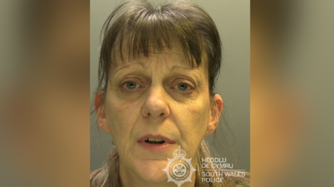 Custody photograph of Tracy Turner, 52. She has brown hair pulled back in a ponytail, with a brown full fringe. She has blue eyes, wears a nose ring and looks at the camera. 