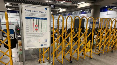 Yellow metal gates pulled across barriers near a 'strike action impacts' sign