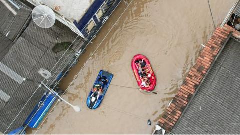 People in inflatable rafts floating on flood water