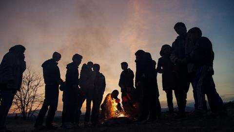 Migrants and refugees keep warm around a bonfire as they wait to enter a registration camp after crossing the Greek-Macedonian border near Gevgelija on 15 November 2015