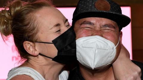 Two people with joyful expressions reunite at Sydney Airport