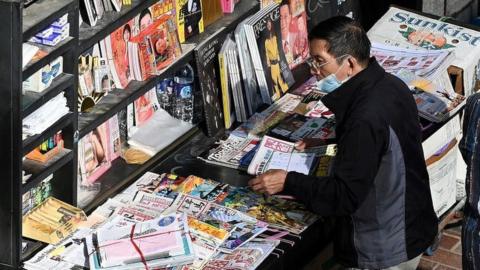 A seller sorts newspapers at a newsstand in Hong Kong