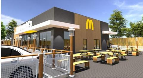 An illustration of what the restaurant could look like if approved at Honiton's Heathpark Industrial Estate. There are benches outside the building which features McDonald's branding.