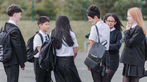 Six school children chatting in a playground.