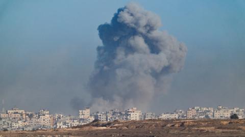 A skyline in Gaza showing a big cloud over buildings after an explosion