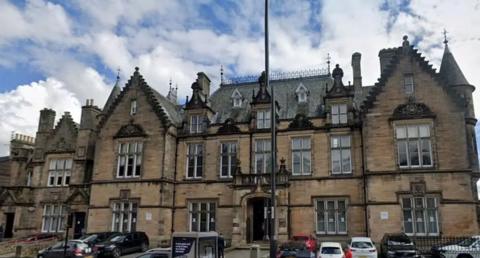 A large court building with two towers and a car park