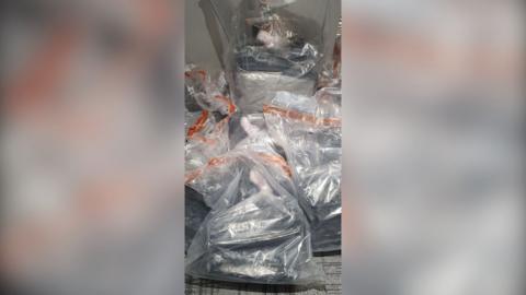 Bags of suspected drugs lie on a floor. 