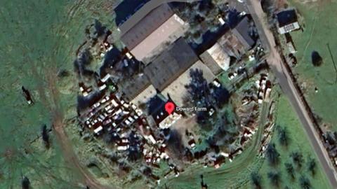 An aerial view of a farm with lots of cars parked outside it.
