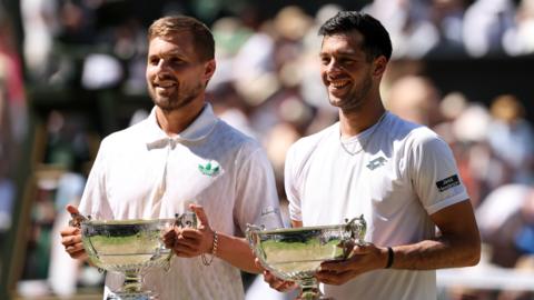 Lloyd Glasspool and Julian Cash holding their men's doubles titles at Wimbledon's Centre Court