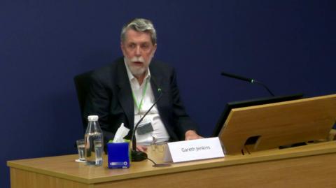 Gareth Jenkins sitting in front of the desk in the room where the Post Office inquiry is being held