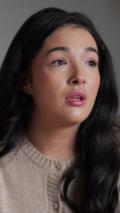 A woman with brown hair wearing a cream cardigan.