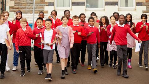  A group of school children in a playground holding micro:bits