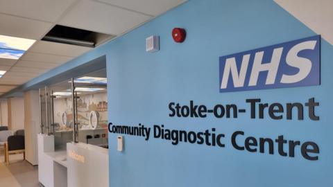 General view of a an entrance to a medical centre. On a blue section of wall the words NHS Stoke-on-Trent Community Diagnostic Centre