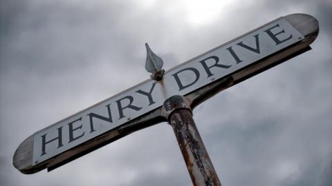 The Henry Drive sign beneath a moody grey sky