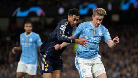 Jude Bellingham and Kevin de Bruyne duel for the ball