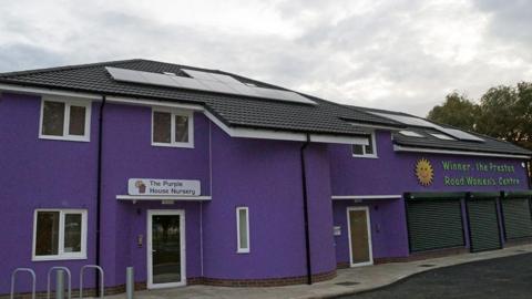 The Preston Road Women's Centre - a building painted in purple with a black tiled roof that has solar panels on it.