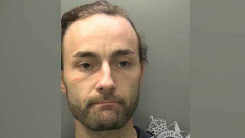 A police image of a man with dark hair and stubble