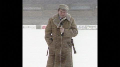 John Motson wears his sheepskin coat during a snow shower