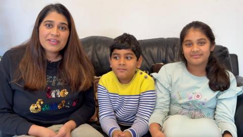 Pooja (left) and her son (middle) and daughter (right) on the sofa.
