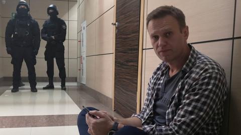 Alexei Navalny sits on the floor outside the office of his Anti-Corruption Foundation during a police raid in Moscow, 26 December 2019