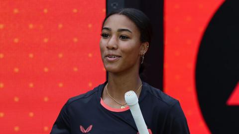 Davina Perrin walks out to bat for Birmingham Phoenix in front of an LED screen featuring the franchise's badge