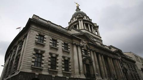 The outside of the Old Bailey. It's a grand-looking grey stone building with a tower of white pillars with a gold statue on top.