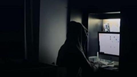 Man in a dark room looking at a computer screen