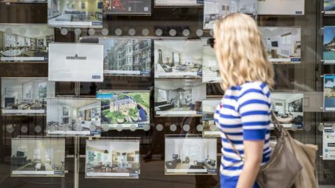 Woman looking inside an estate agent's window