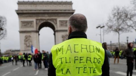 A protester wearing a Yellow Vest (Gilet Jaune) reading "Macron, you"re losing your (head) mind, remember 1789 (refering to the French Revolution) during an anti-government demonstration called by the Yellow Vest movement next to the Arc de Triomphe in Paris, on January 12, 2019. -