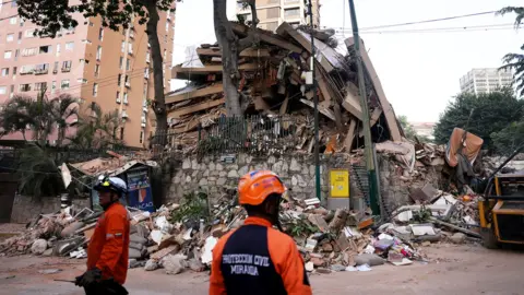 Emergency services work at the site of a collapsed building after earthquakes hit the country, in Caracas, Venezuela,