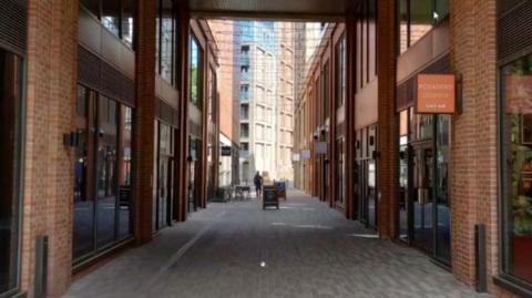 An alley in a new-build complex with shop sites either side.