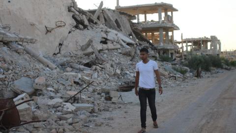 Moawiya Sayasina, a Syrian activist, walks past destroyed buildings in a rebel-held district in the southern Syrian city of Deraa on 5 June 2018