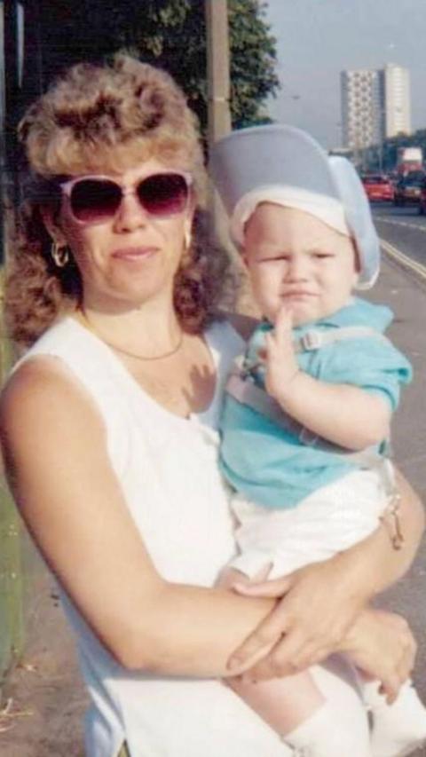 A slightly faded photograph of Shane as a baby with his mum.