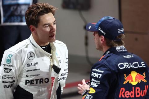 George Russell and Max Verstappen talk to each other in the pit lane