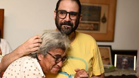 Alaa Abd El Fattah pictured hugging his mother after being released as a hostage wearing a yellow t-shirt