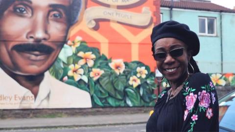 Judy Evans in front of her father's mural