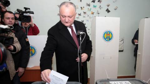 Igor Dodon, flanked by TV cameras, places his ballot paper into a ballot box