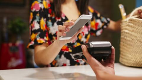 Customer paying cashless with smartphone at counter of a store