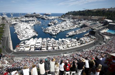 Yachts in the harbour in Monaco with spectators in the grandstand watching the grand prix below them