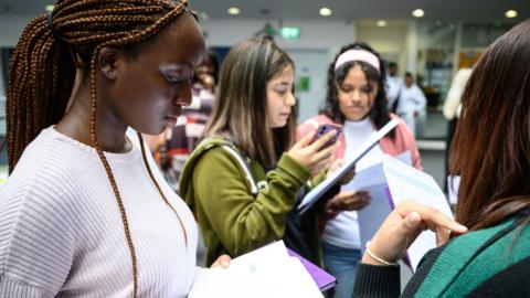 Female students stand around looking at their GCSE results at the City of London Academy Southwark.