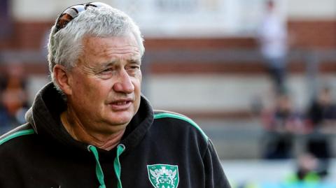 Chris Boyd wearing his black and green Northampton Saints hoodie looks on from the touchline during his time as the club's director of rugby