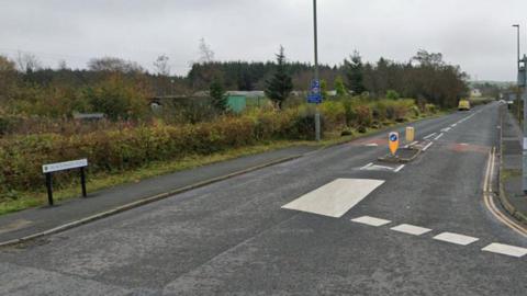 View of Blacksnape Road in Hoddlesden, Darwen. There are allotments on one side of the road and a junction.