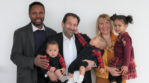 Professor Kypros Nicolaides stands between Mr and Mrs Ahouansou while he holds their twin boys in his arms