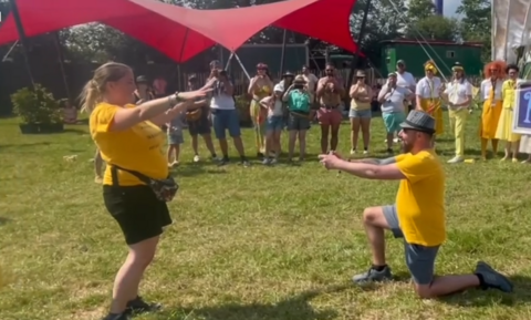 Mr Wilson on one knee holding out a ring while Ms Lawrence waves her arms excitedly