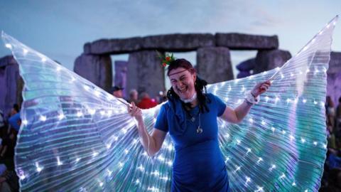 A woman witg butterfly wings in front of Stonehenge